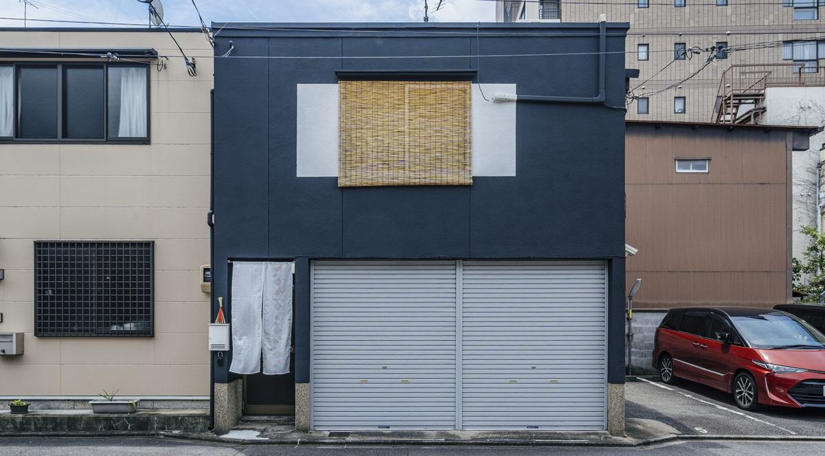 The navy facade with two silver shutters and a white noren to the left
